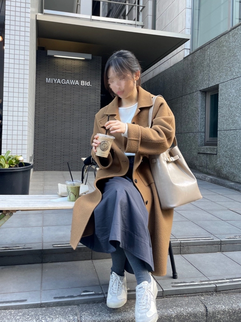갈색 코트를 입고 벤치에 앉아 음료를 든 와이프의 여행 사진.